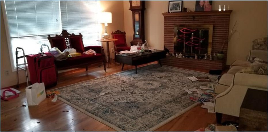 A cluttered living room before a CCR clean, belongings and litter across the floor