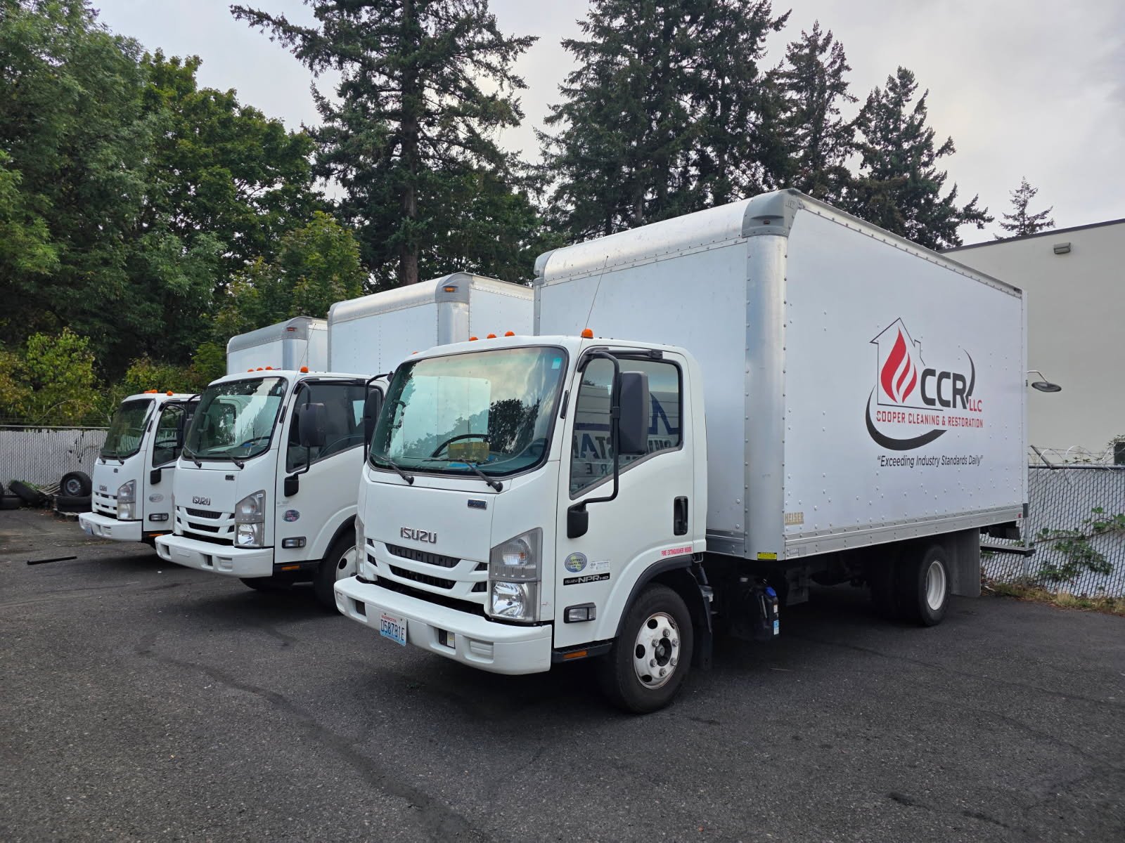 Three CCR box trucks lined up, the company logo on the nearest one