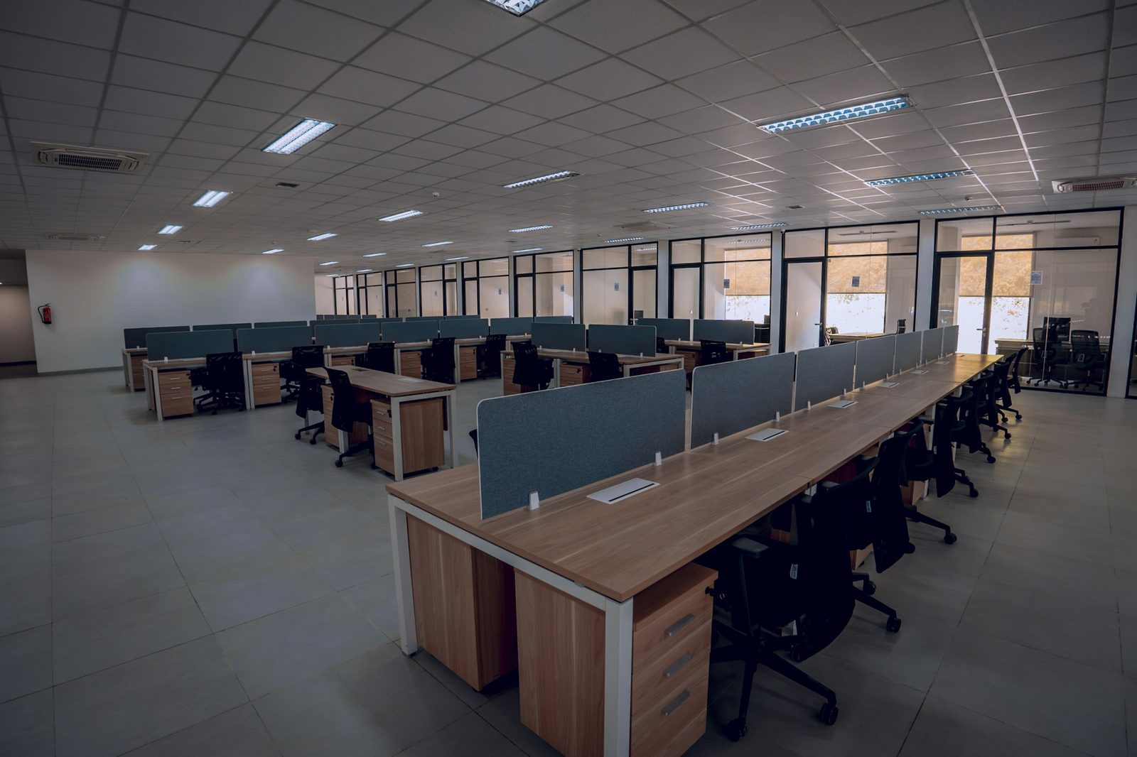 An empty open-plan office floor, desks and chairs in rows, no one at work