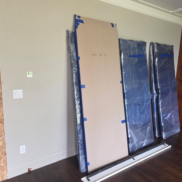 Padded and plastic-wrapped panels standing in a home mid-repair